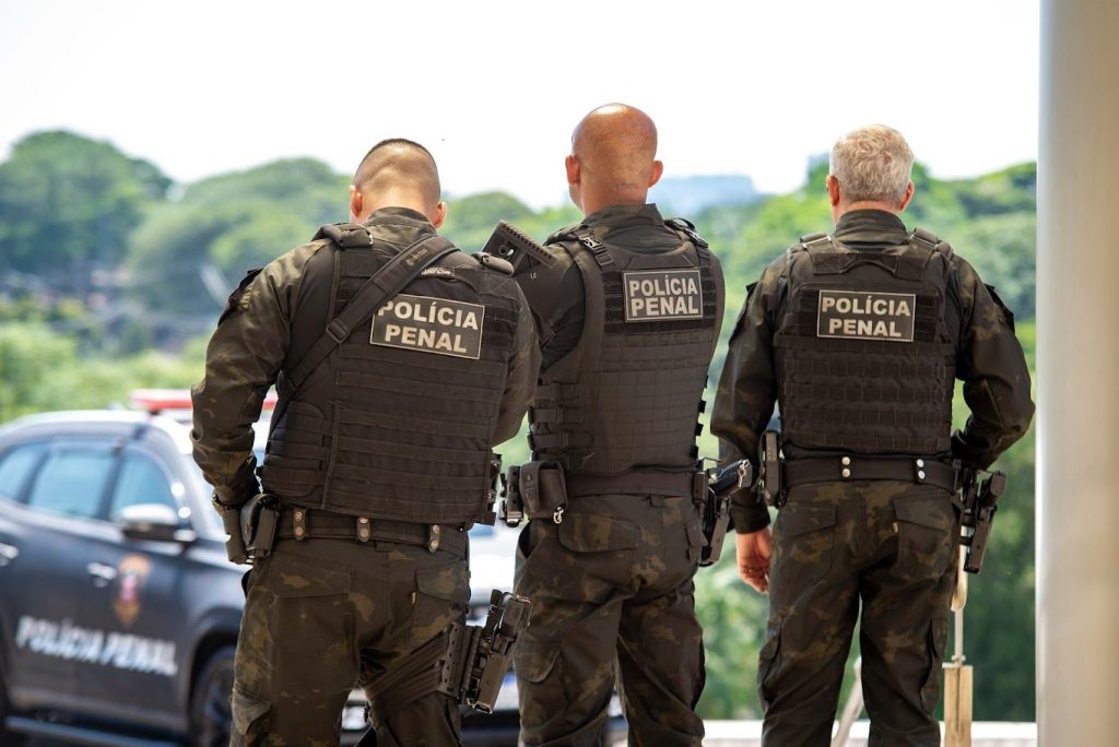Policial penal em frente a tela com gráfico de salários por estado
