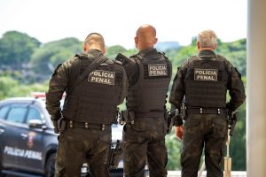 Policial penal em frente a tela com gráfico de salários por estado