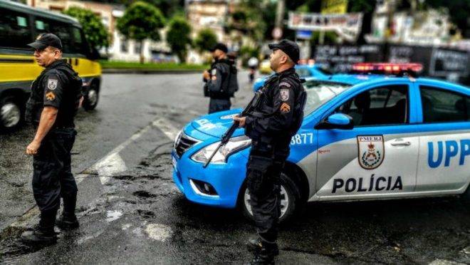 Candidato estudando para concurso da PMERJ com viatura policial ao fundo