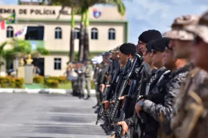 Candidato analisando edital da PMAL 2026 ao lado de uniforme e itens policiais em mesa organizada