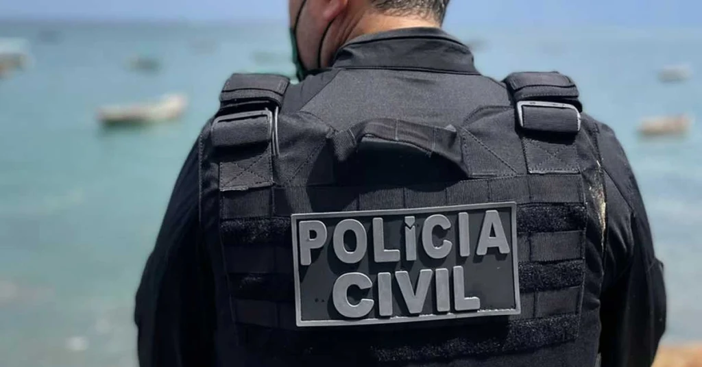 Concurseiro observando prédio da Polícia Civil da Bahia ao fundo de Salvador à noite